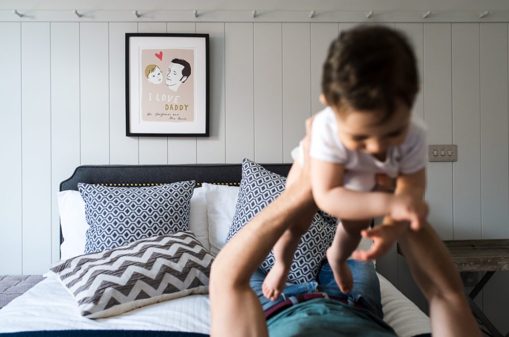parent and child playing on bed