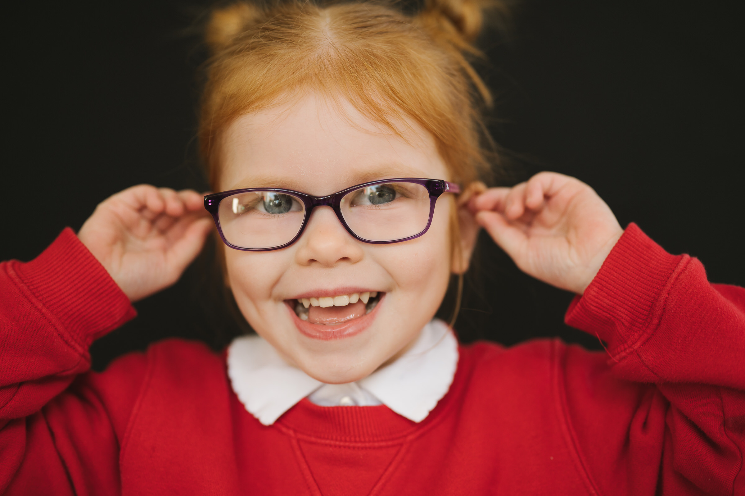School portrait of girl playing with her glasses