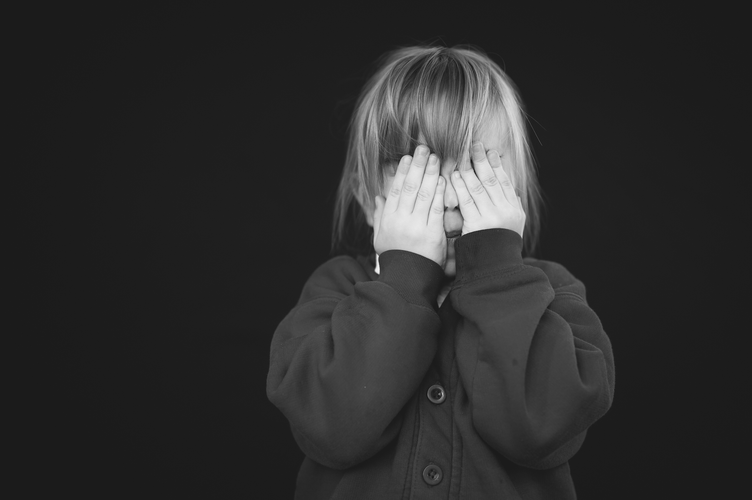 School portrait of girl hiding behind her hands