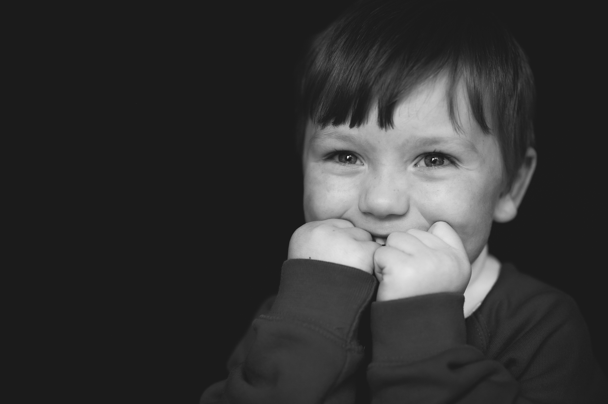 Boy giggling shyly behind hands