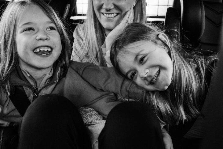 Mum in back of car with two children